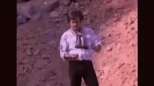 Man In White Shirt Holding Binoculars On Rocky Hill GIF