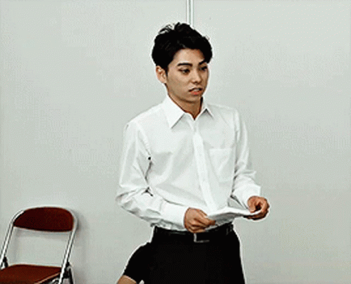 Man in White Shirt Holding Paper Near Chair