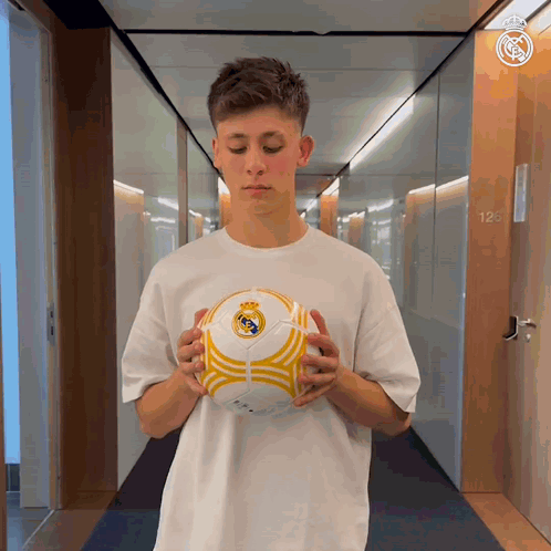 Man in White Shirt Holding Soccer Ball Hallway
