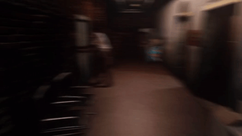 Man in White Shirt in Dark Hallway With Elevator Sign