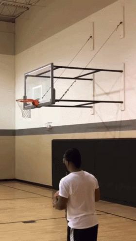 Man in White Shirt in Front of Basketball Hoop