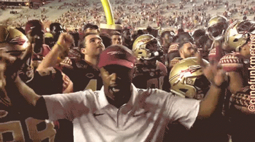 Man in White Shirt in Front of Football Helmets