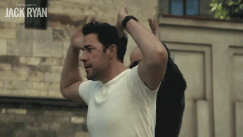 Man In White Shirt In Front Of Jack Ryan Wall GIF