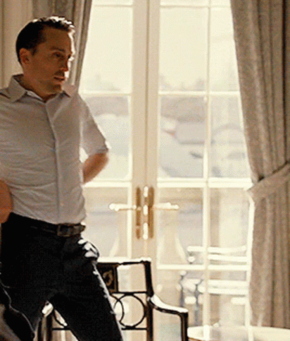 Man In White Shirt In Front Of Large Window GIF