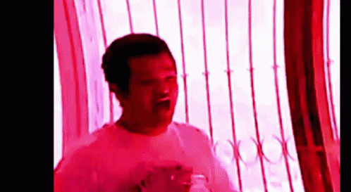 Man in White Shirt in Front of Window with Red Light