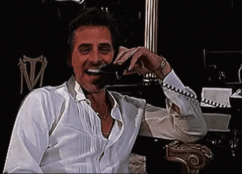 Man in White Shirt Laughing and Talking on Phone