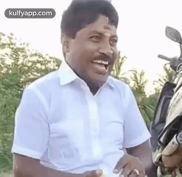 Man in White Shirt Laughing Next to Motorcycle