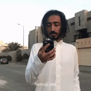 Man in White Shirt Looking at Phone with Hemoji.net