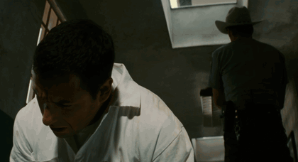 Man in White Shirt Looking Down With Cowboy Behind