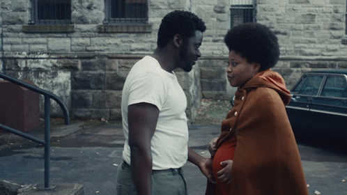 Man In White Shirt Next To Pregnant Woman In Brown Blanket GIF