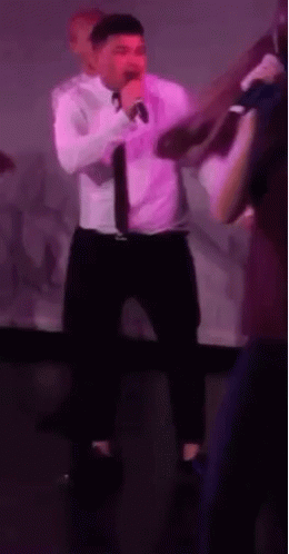 Man in White Shirt Singing Into Microphone