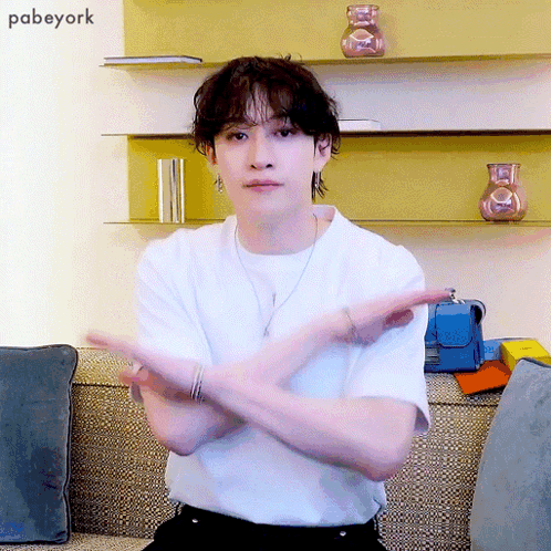 Man In White Shirt Sitting Arms Crossed In Front Of Pabeyork Wall GIF
