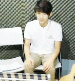 Man in White Shirt Sitting Next to Guitar