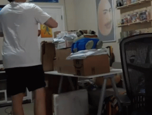 Man in White Shirt Standing at Table with Boxes