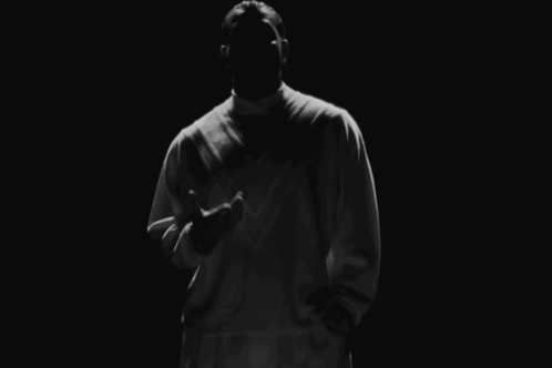 Man in White Shirt Standing in Darkness