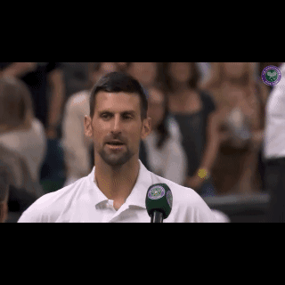 Man in White Shirt Talking Into Microphone With Wimbledon Logo