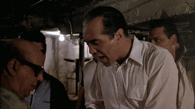 Man in White Shirt Talking to Another in Dark Room