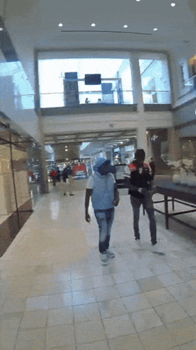 Man In White Shirt Walking Down Hallway GIF