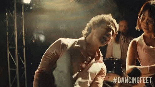 Man In White Shirt With Bottles Sitting On Couch Hands Folded GIF
