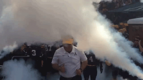 Man in White Shirt With Letter A Walking Through Smoke