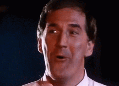 Man In White Singing Funny Face Into Microphone GIF
