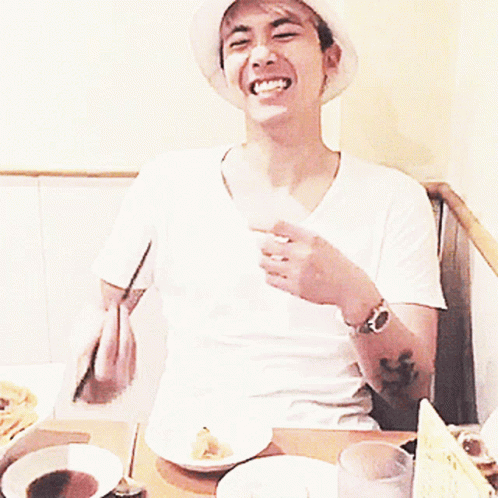 Man in White Sophnet Hat Eating with Chopsticks
