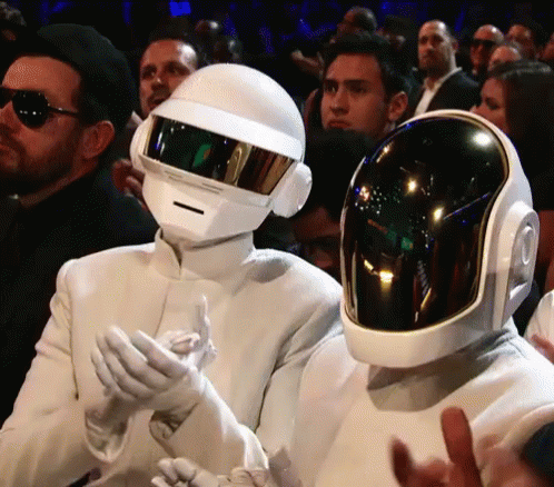Man in White Suit and Helmet Next to Another Man in Helmet