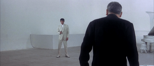 Man in White Suit in Front of Piano