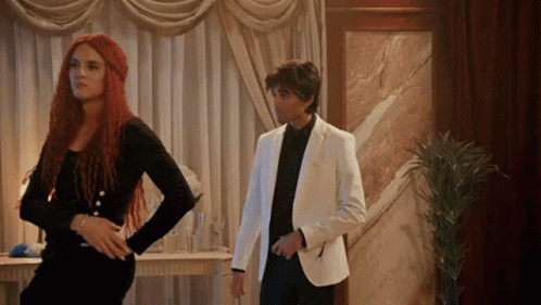 Man In White Suit Next To Woman With Red Hair GIF