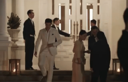 Man in White Suit Walking Down Stairs with Woman in Red Dress