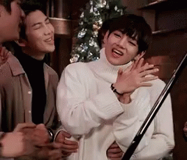 Man in White Sweater Laughing Next to Two Men