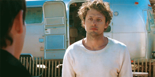 Man in White Sweater Standing in Front of Trailer