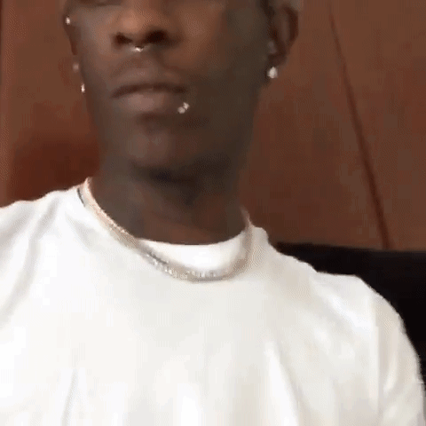 Man In White T-Shirt And Necklace Sitting Down GIF