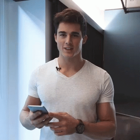 Man in White T-Shirt Holding Cell Phone