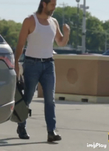 Man in White Tank Top and Blue Jeans Walking