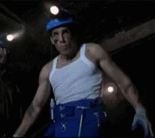 Man In White Tank Top And Blue Pants Standing In Dark Room GIF