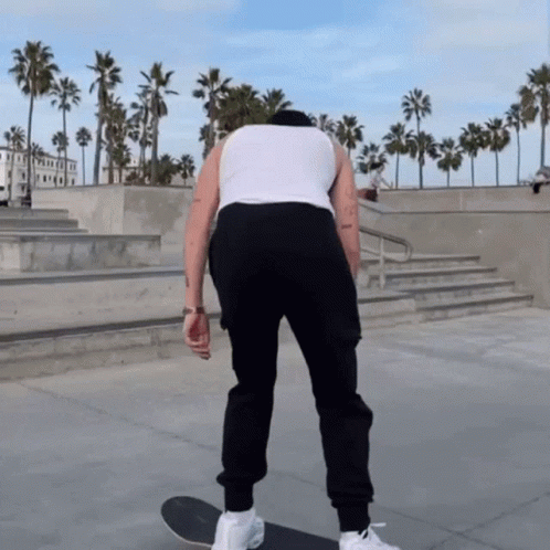 Man in White Tank Top, Black Pants Skateboarding