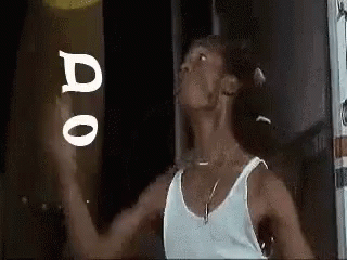 Man in White Tank Top Holding Frisbee in Front of Do Sign