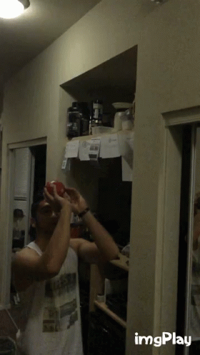 Man in White Tank Top Holding Red Apple