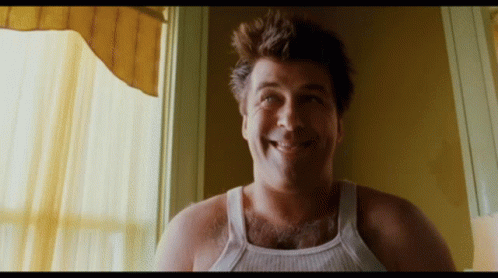 Man in White Tank Top Smiling Out Window