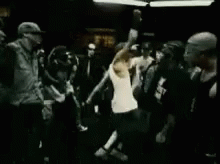 Man In White Tank Top Standing Before Crowd In Dark Room GIF