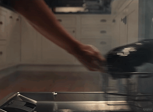 Man In White Tank Top Standing In Kitchen Holding Bottle GIF