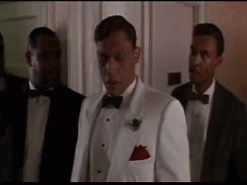 Man in White Tuxedo Next to Two Men in Suits