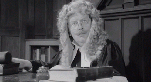 Man In Wig And Glasses At Desk With Book GIF