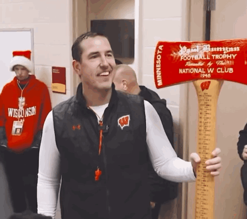 Man in Wisconsin Vest Holding Axe