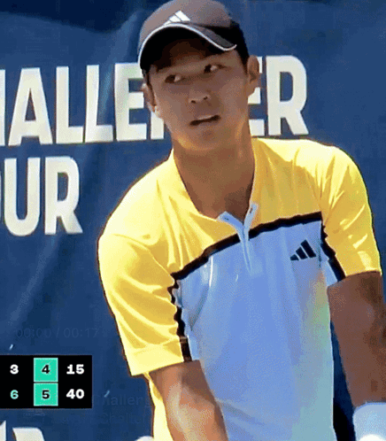 Man in Yellow Adidas Shirt Playing Tennis in Front of Halle Ur Banner