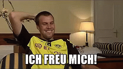 Man in Yellow and Black Shirt Sitting on Bed With Arms Over Head Ich Freu Mich