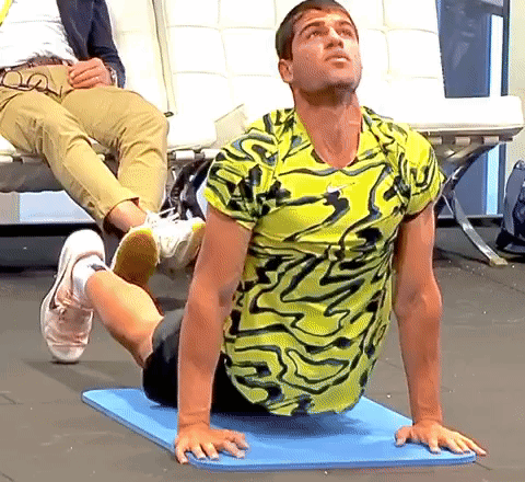 Man In Yellow And Black Shirt Stretching GIF