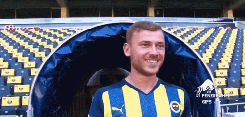 Man In Yellow Blue Striped Shirt Smiling In Stadium GIF