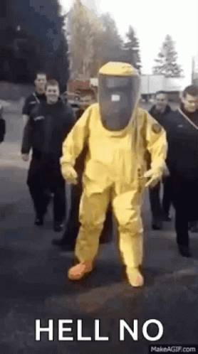 Man in Yellow Hazmat Suit Walking With Group